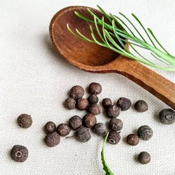 liegende Pimentkörner neben einem Holzlöffel
