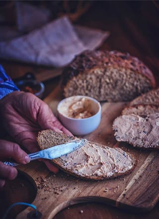 Brotstück, das mit Aufstrich bestrichen wird