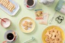 Джинджифилови бисквити върху чиния за торта и комплект чаши за кафе в пастелни цветове.