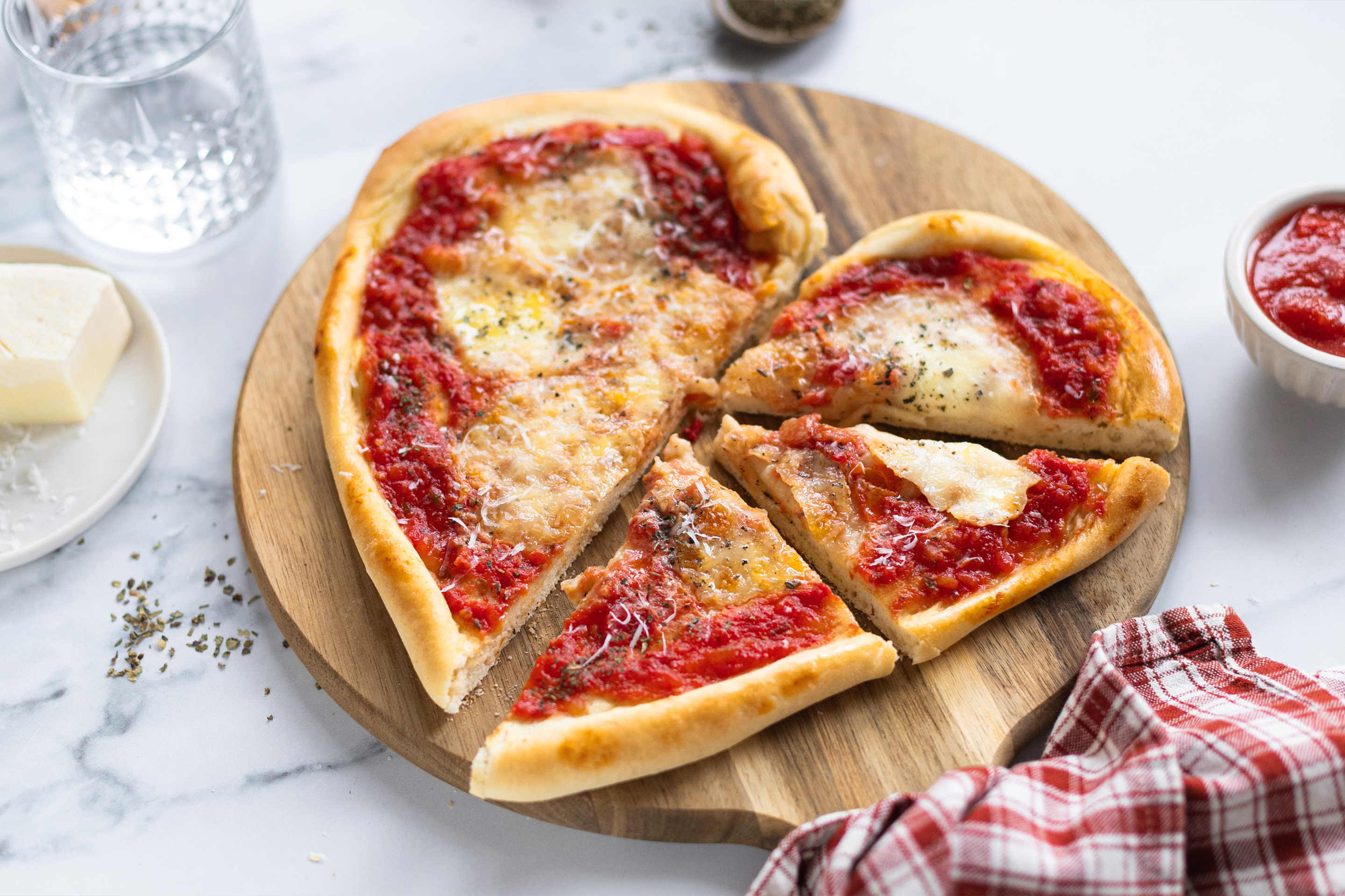 Пица Маргарита във формата на сърце, сервирана върху дъска, на която половината от сърцето е нарязано на три парчета.