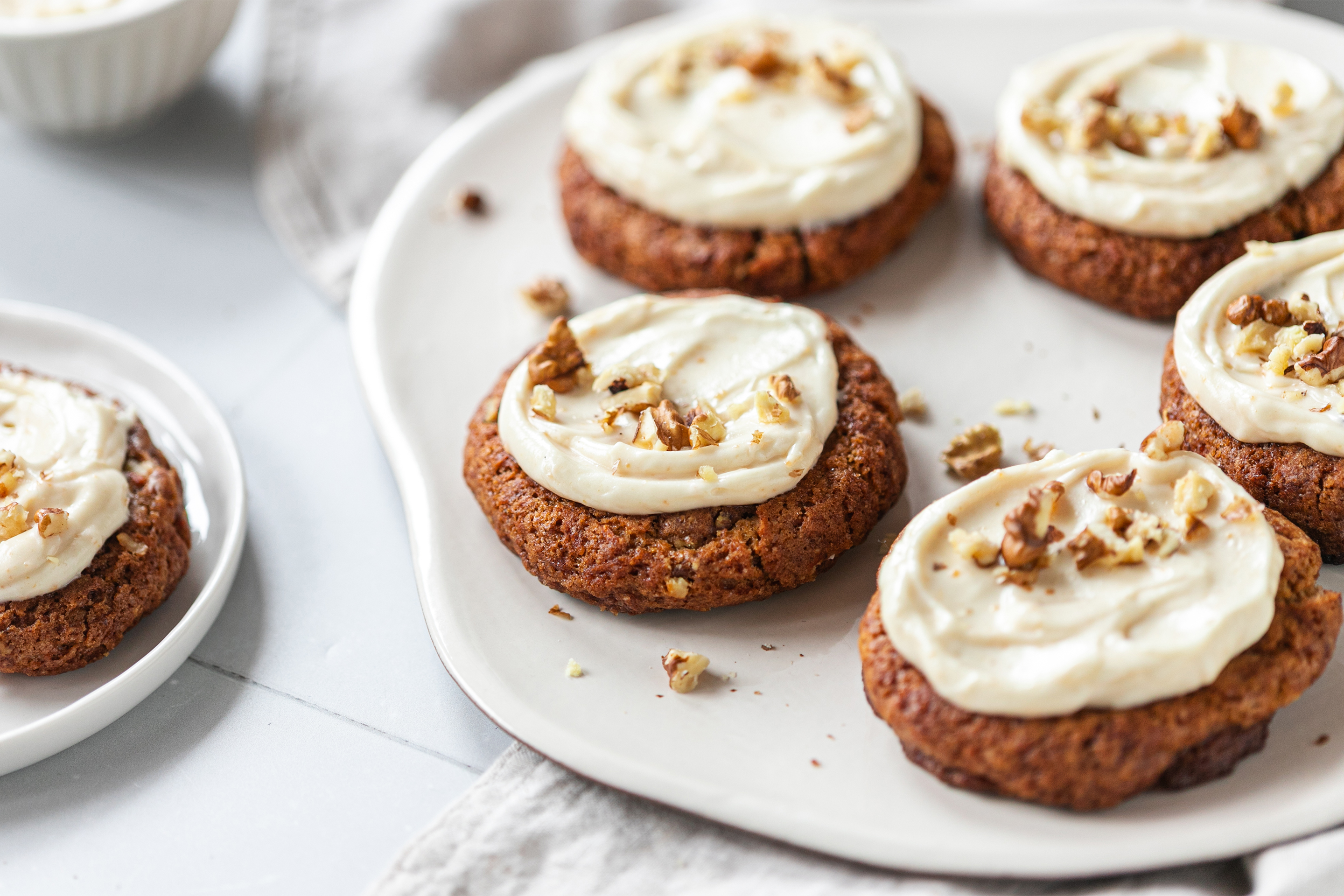 Порция кафеникави курабийки, намазани с бял сладкарски крем и поръсени с накълцан шамфъстък.